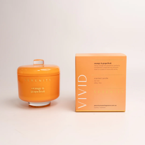 Orange candle with lid and packaging on a light background